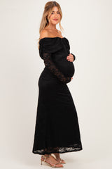 woman wearing a black off-shoulder maternity gown with lace details and holding her baby bump