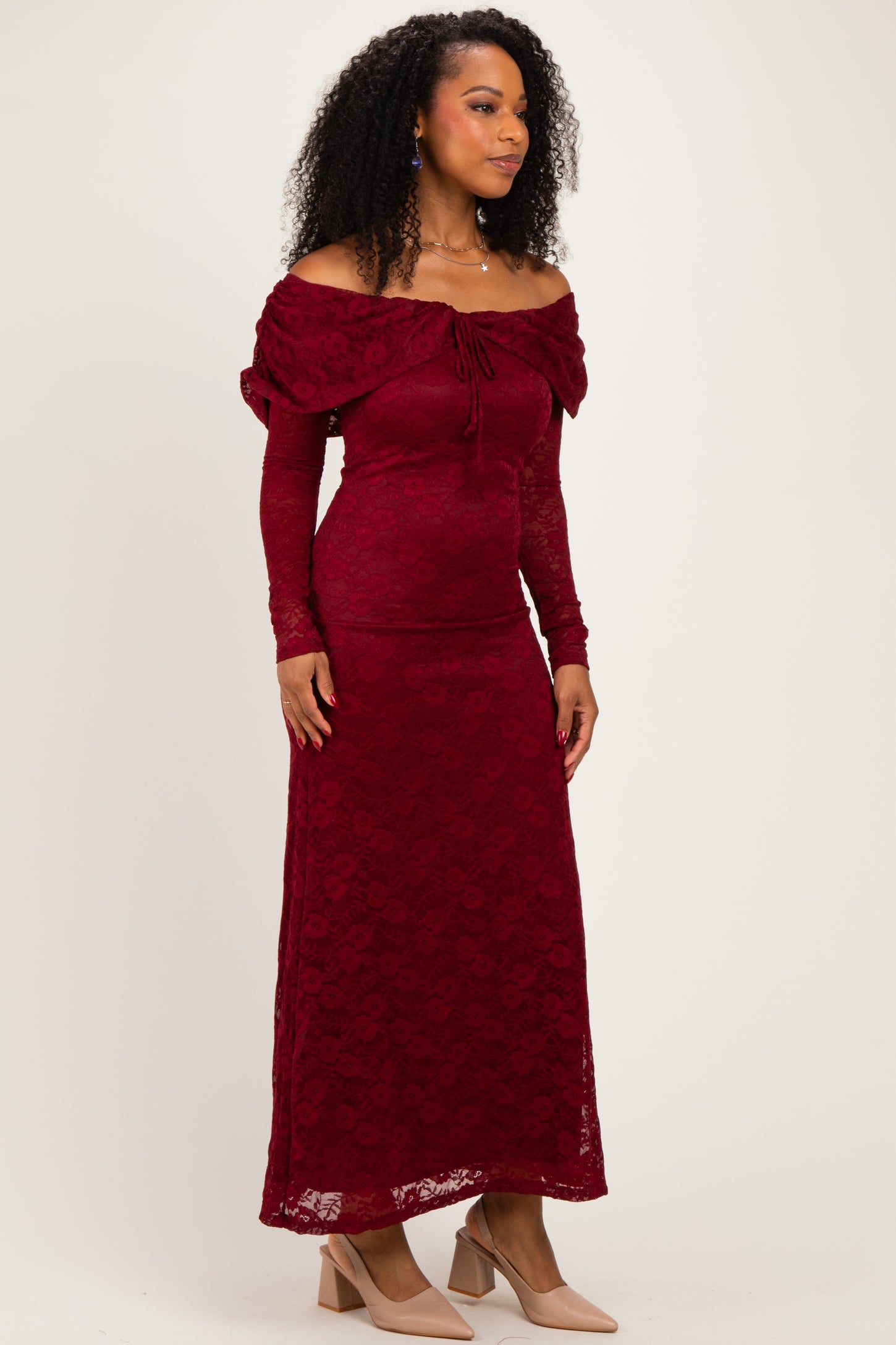 woman wearing a burgundy off-the-shoulder lace gown with long sleeves and fitted silhouette