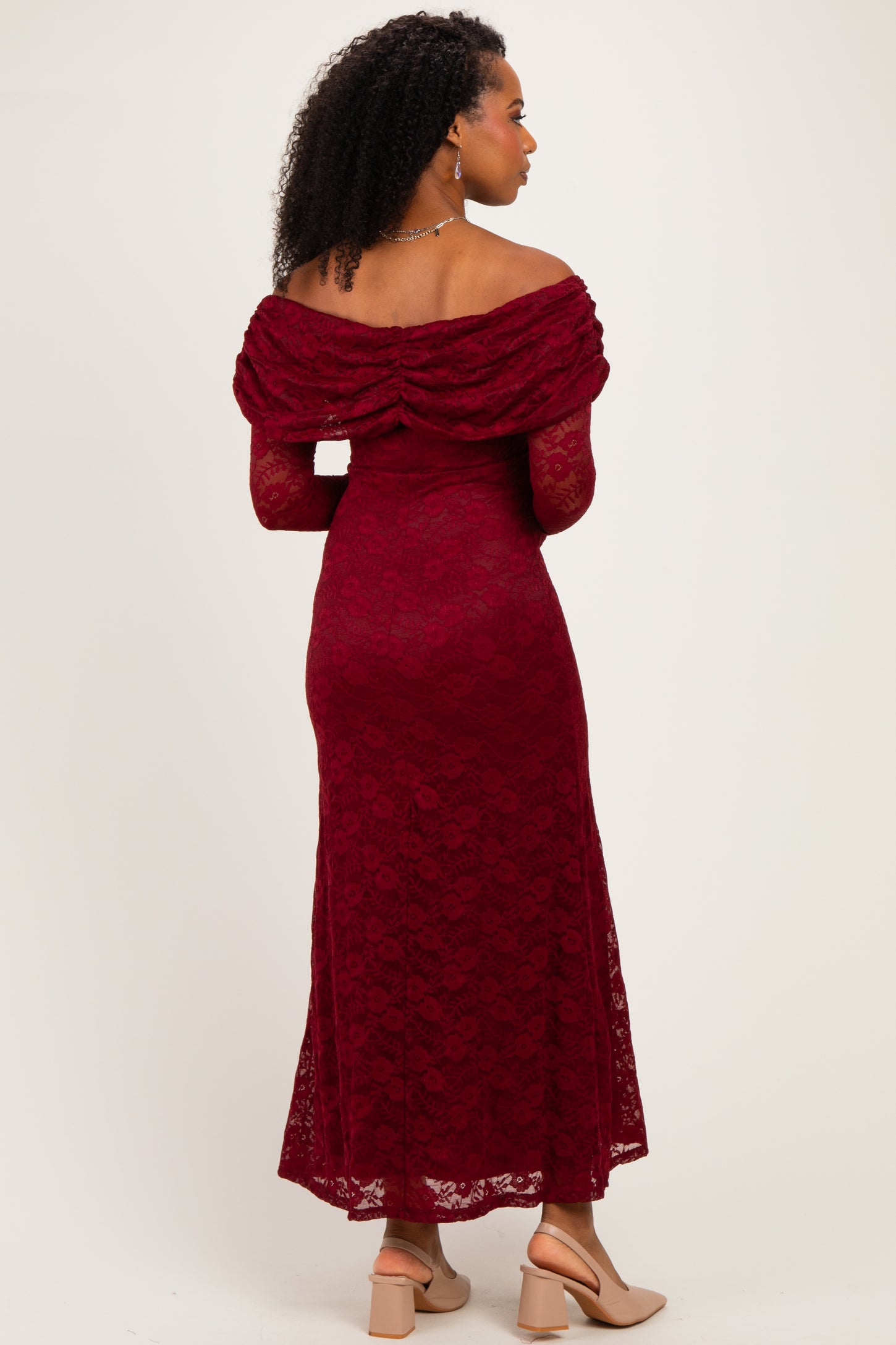 woman wearing a burgundy lace off-the-shoulder maxi dress with a fitted bodice and flowing skirt, seen from the back
