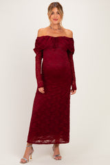 woman wearing a burgundy off-shoulder maternity gown with long lace sleeves and a visible baby bump
