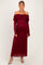 woman wearing a burgundy off-shoulder maternity gown with long lace sleeves and a visible baby bump