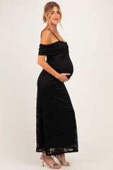 woman wearing a black off-shoulder maternity dress, showcasing her baby bump with a fitted silhouette and lace details