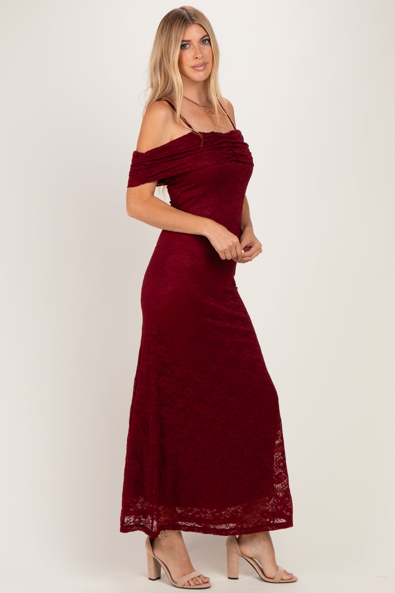 woman wearing a burgundy off-the-shoulder lace maxi dress with a fitted bodice and flowing skirt