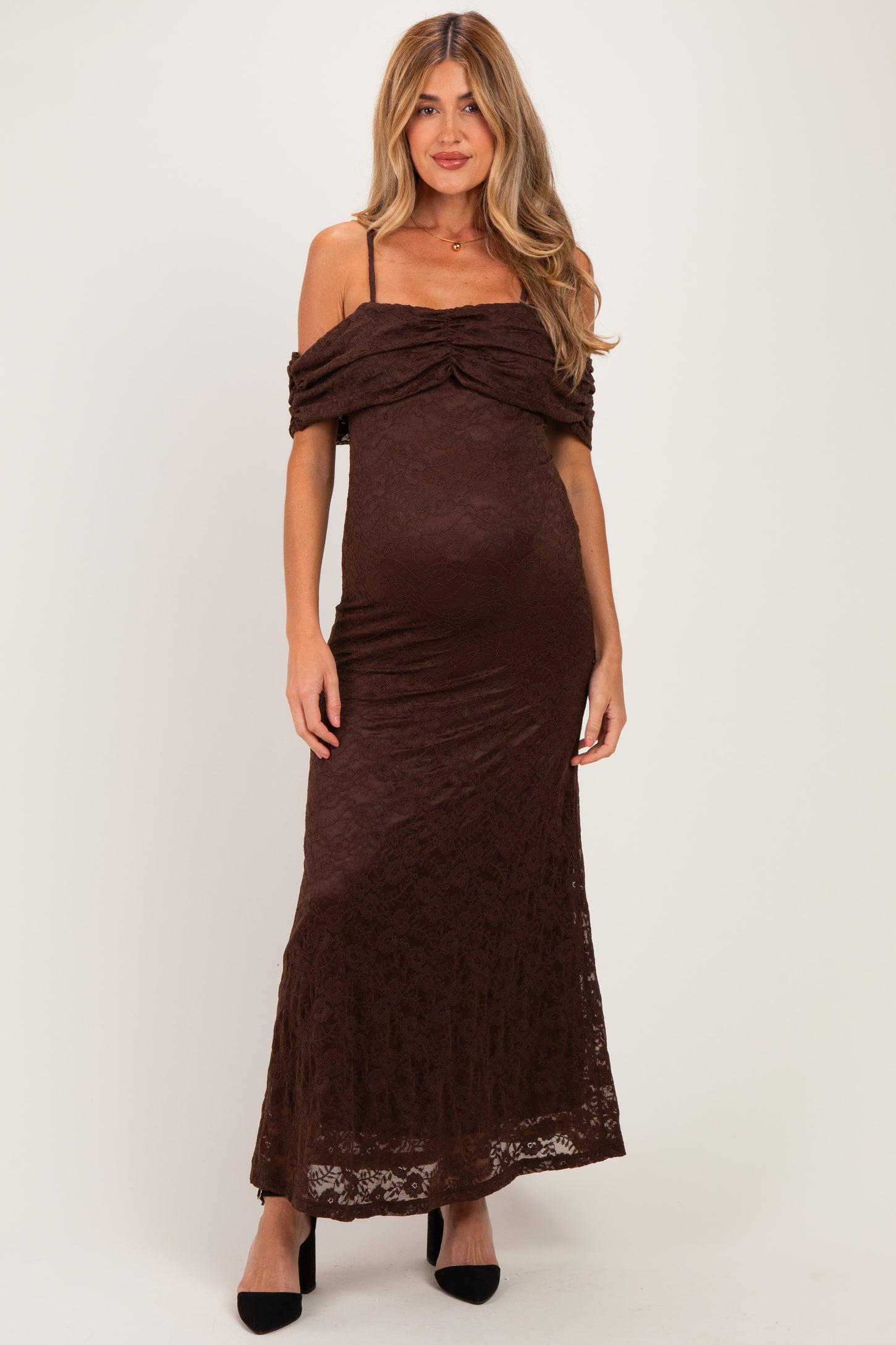 woman wearing a brown lace maternity maxi dress with off-the-shoulder straps and a fitted silhouette, showing her baby bump