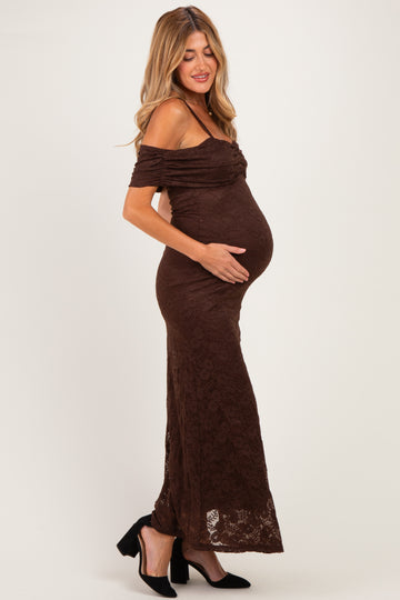 woman wearing a brown off-the-shoulder lace maternity dress and holding her baby bump