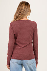 woman wearing a maroon and black striped maternity top with long sleeves, showing the back view