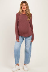 woman wearing a burgundy striped long sleeve maternity top and light blue wide-leg jeans, showing her baby bump
