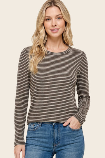 woman wearing a brown striped long sleeve top with a round neckline and relaxed fit, paired with blue jeans