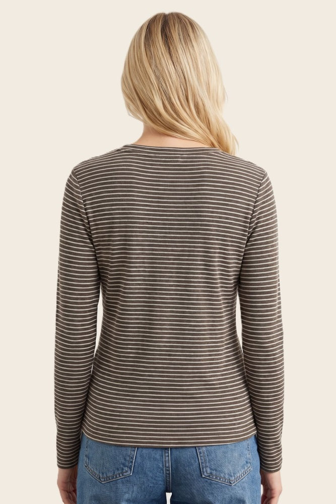 woman wearing a brown and white striped long sleeve top, viewed from the back, paired with blue jeans