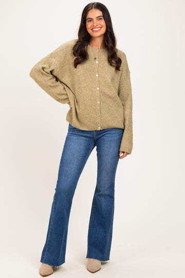 woman wearing a light olive green oversized cardigan with buttons paired with flared blue jeans