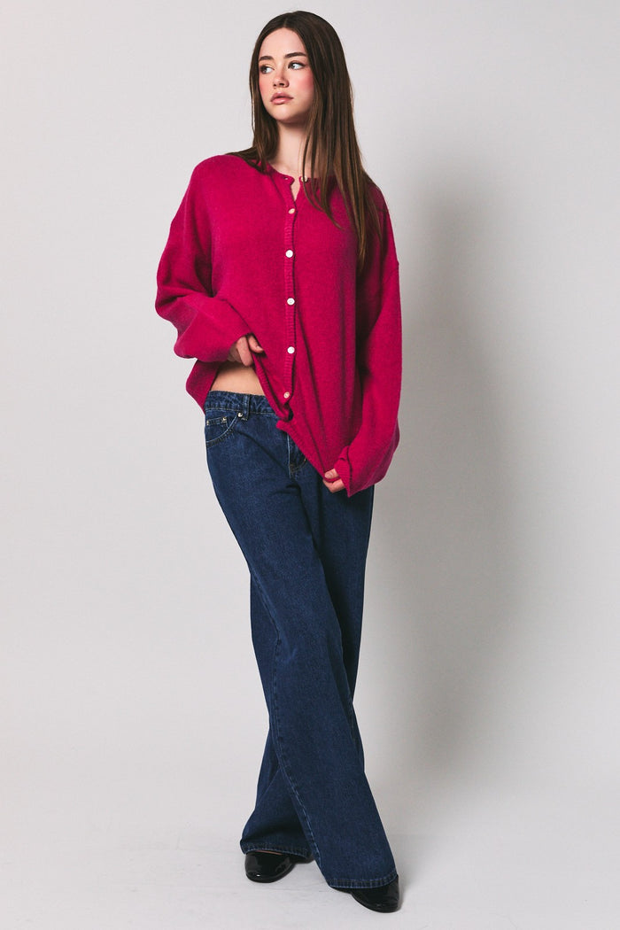 woman wearing a fuchsia oversized cardigan with button details and wide-leg jeans