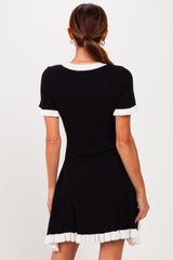 woman wearing a black ribbed short sleeve dress with white ruffle detailing on the sleeves and hem