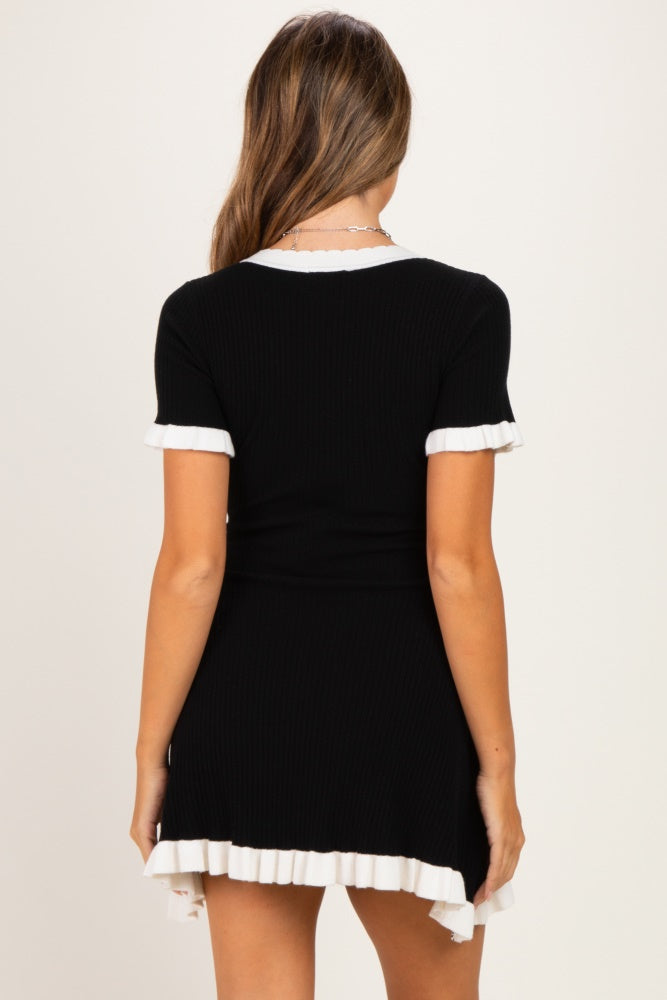 woman wearing a black ribbed maternity dress with white ruffled hem and sleeves, showcasing a baby bump