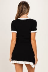 woman wearing a black ribbed maternity dress with white ruffled hem and sleeves, showcasing a baby bump