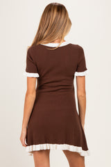 woman wearing a brown ribbed maternity dress with white ruffled details on sleeves and hemline