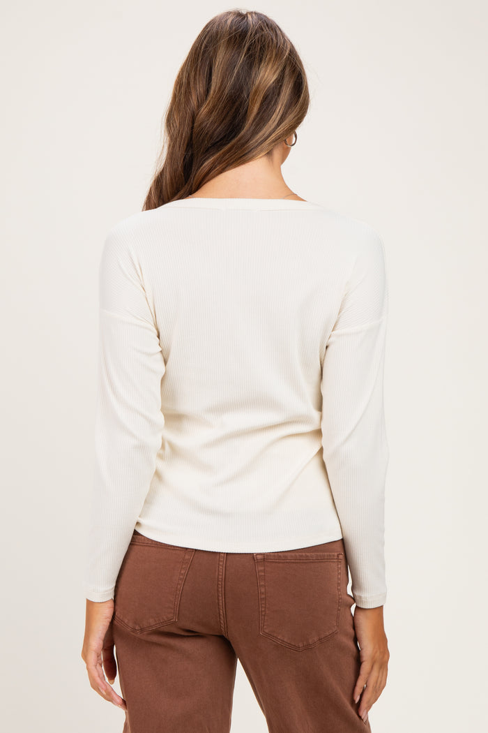 woman wearing a cream long sleeve maternity top, viewed from the back, paired with brown maternity pants