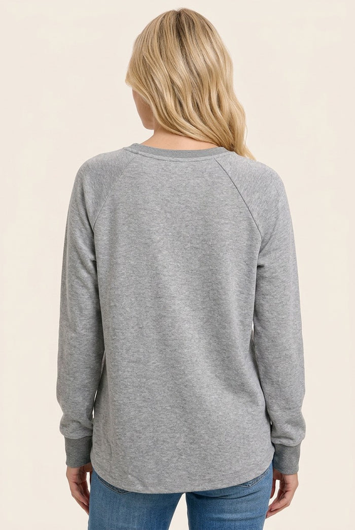 woman wearing a gray long sleeve sweatshirt, viewed from the back, paired with blue jeans