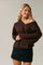 woman wearing a brown off-shoulder oversized sweater with ribbed cuffs and a black mini skirt
