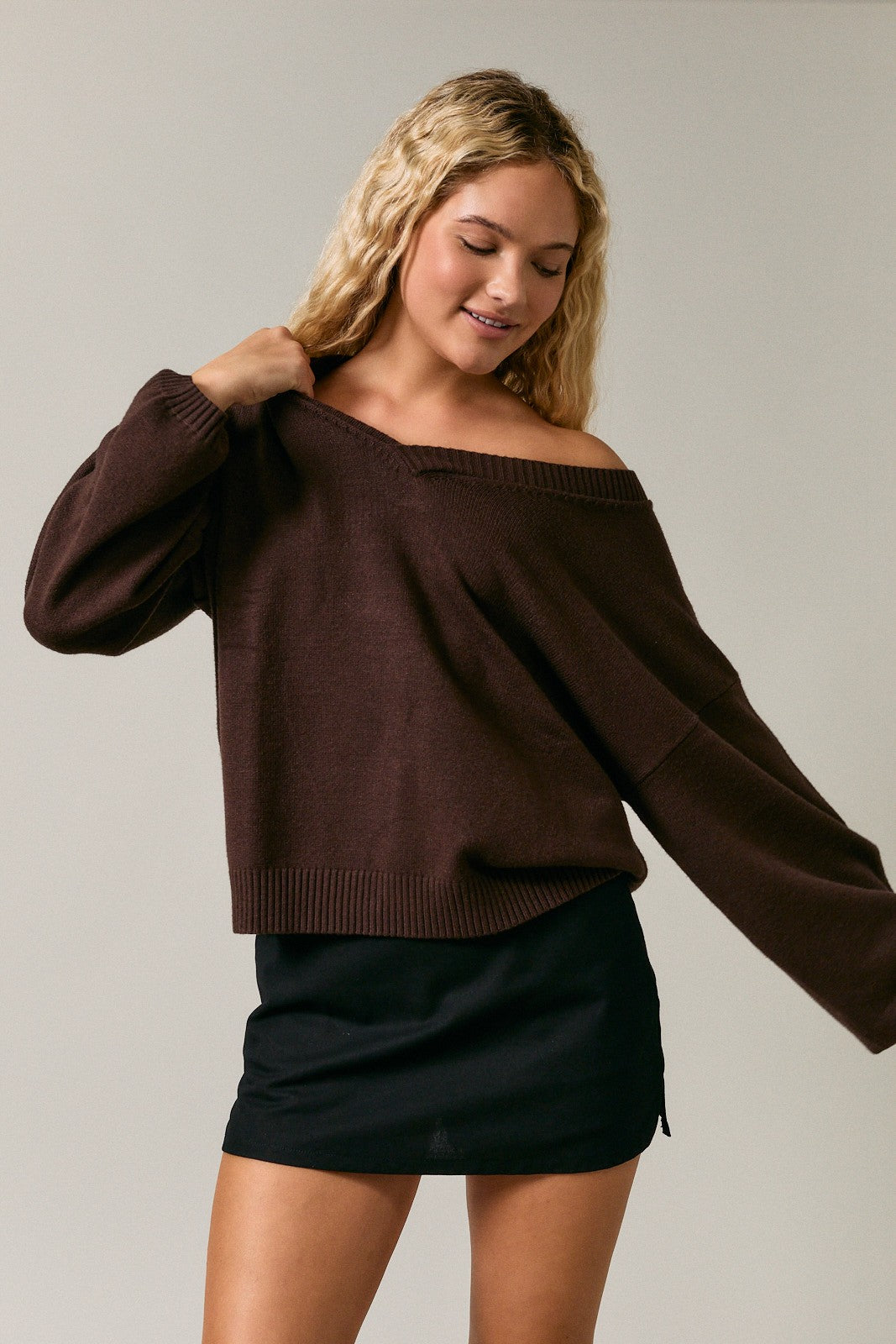 woman wearing a brown off-the-shoulder sweater and a black mini skirt