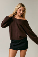 woman wearing a brown off-the-shoulder sweater and a black mini skirt