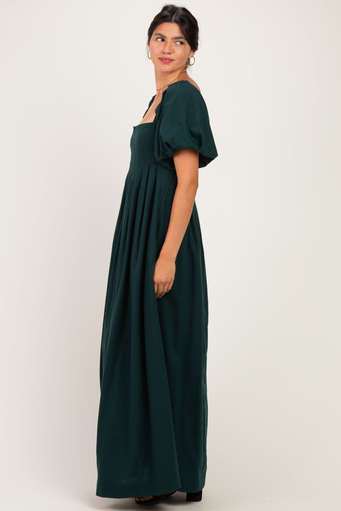 woman wearing a dark green maxi dress with puffed short sleeves and a square neckline