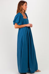 woman wearing a teal maxi dress with puff sleeves and a square neckline
