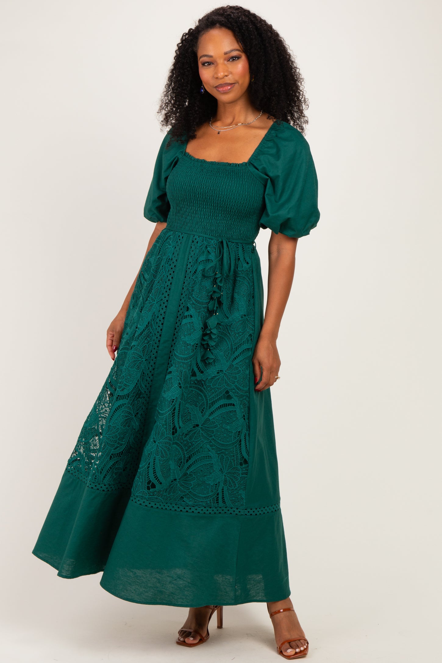 woman wearing a dark green maxi dress with puff sleeves, smocked bodice, and lace details