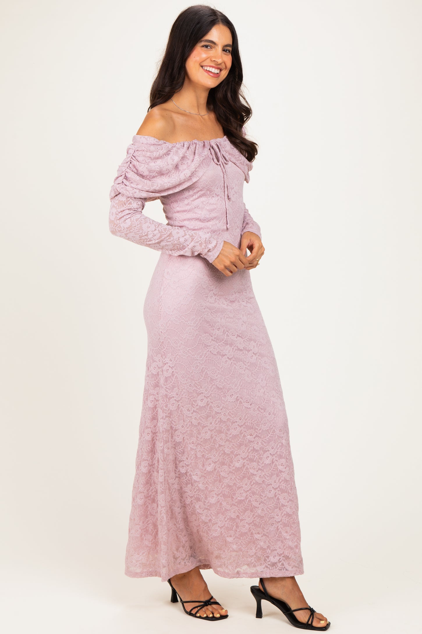 woman wearing a dusty pink off-the-shoulder lace maxi dress with long sleeves and a ruched detail