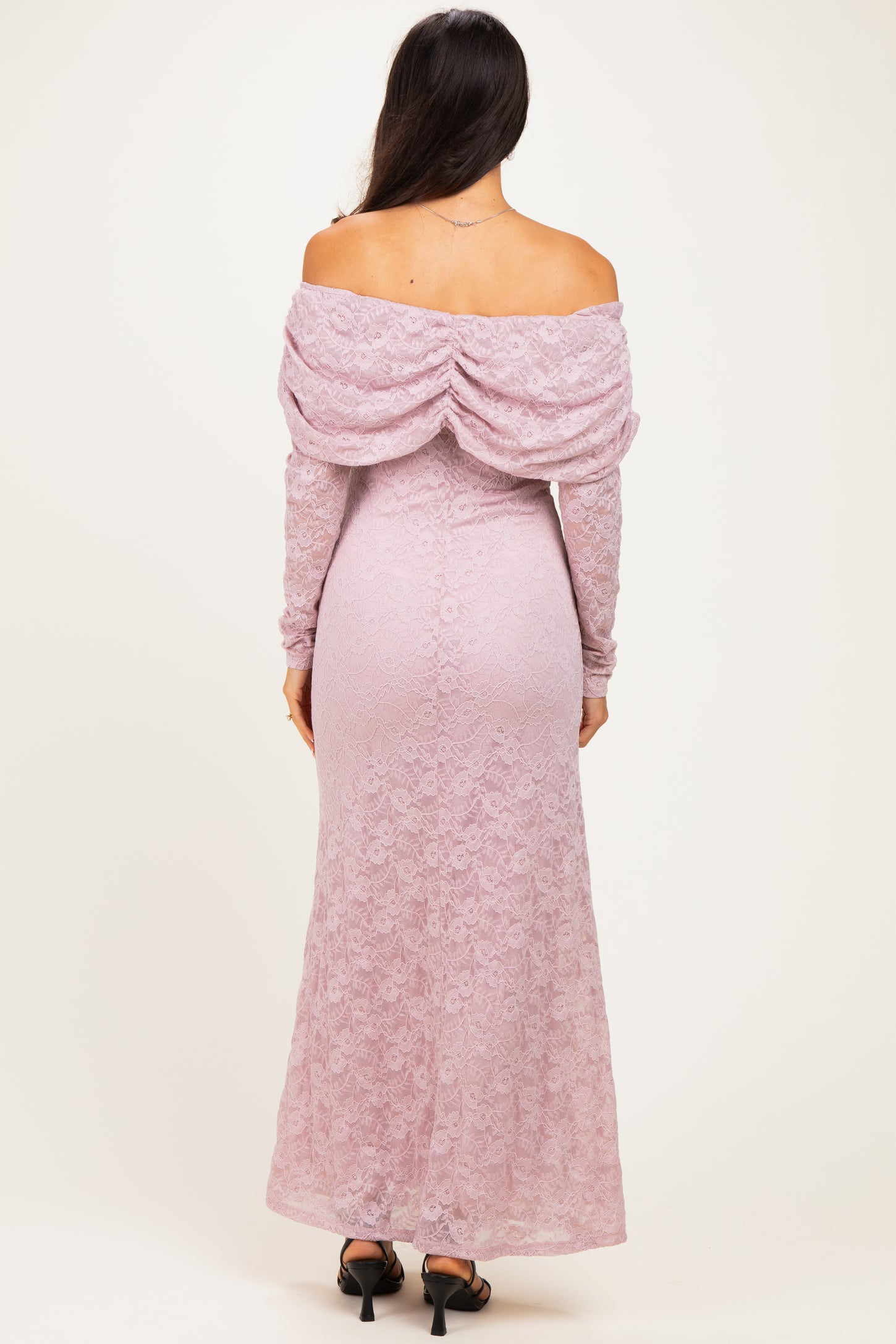 woman wearing a light pink off-the-shoulder lace gown with long sleeves and a draped back detail