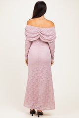 woman wearing a light pink off-the-shoulder lace gown with long sleeves and a draped back detail