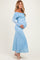woman wearing a light blue off-the-shoulder lace maternity dress and gently holding her baby bump