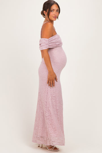 woman wearing a light pink off-shoulder lace maternity gown with a visible baby bump