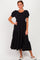 woman wearing a black puff sleeve midi dress with tiered ruffles and a round neckline
