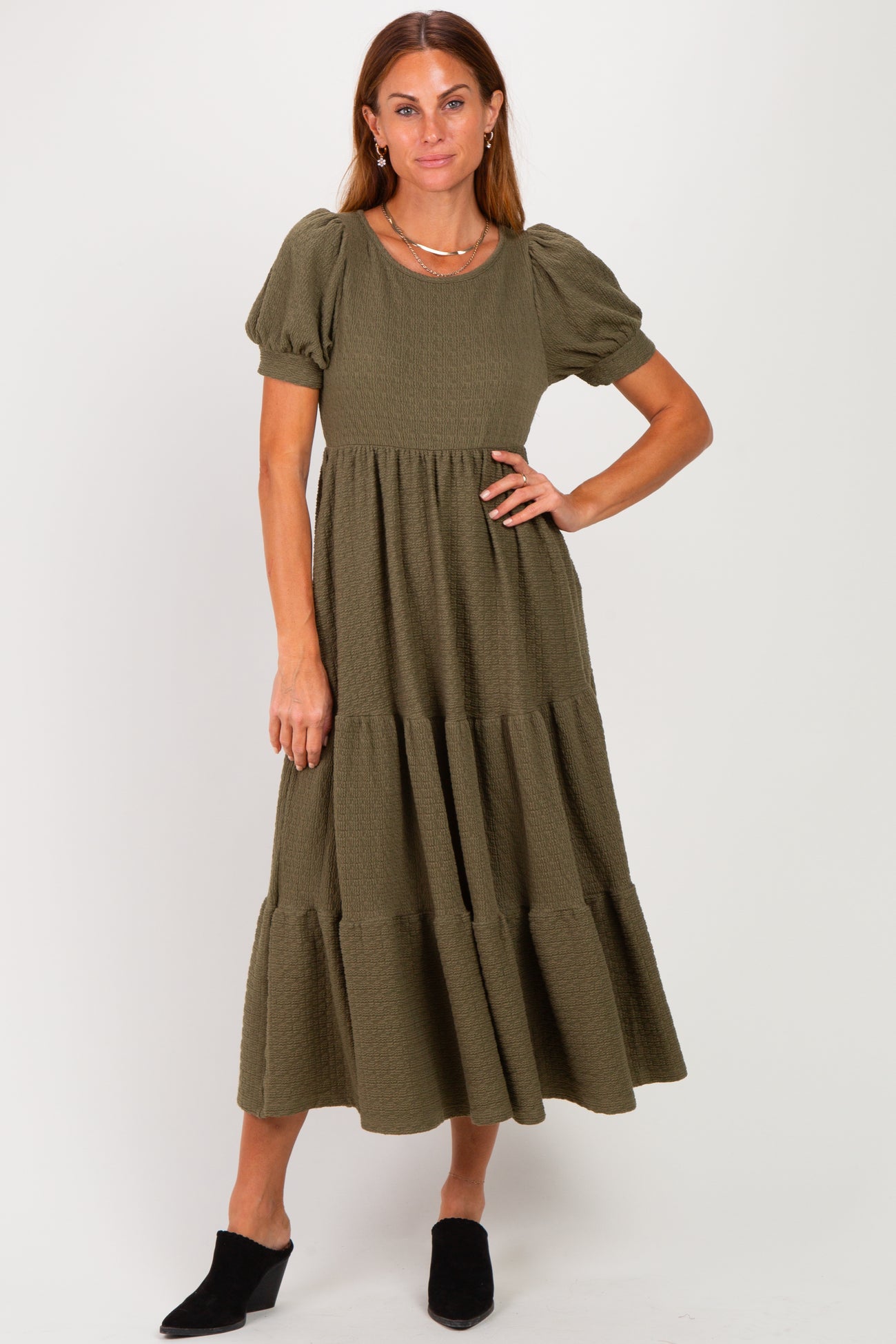 woman wearing an olive green tiered midi dress with short puff sleeves and a textured fabric