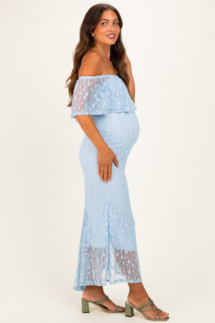 woman wearing a light blue off-shoulder maternity dress with a layered design and a visible baby bump