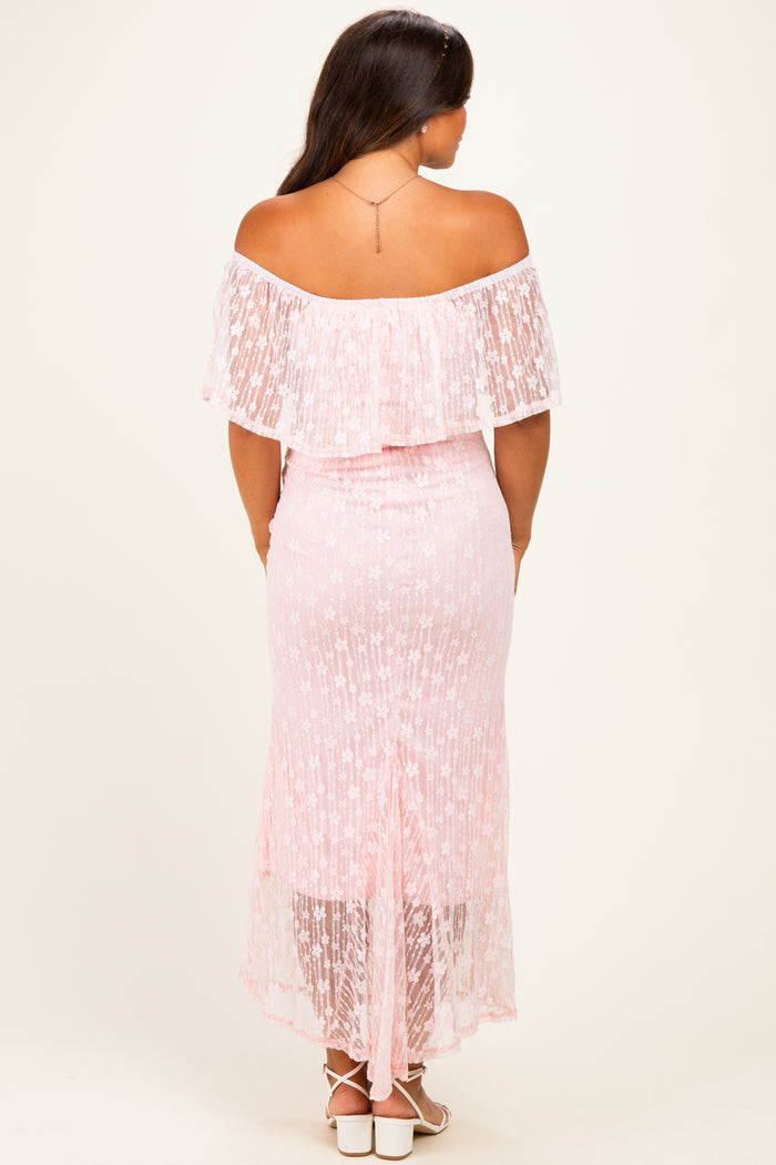 woman wearing a pink off-the-shoulder maternity dress with lace details and a high-low hem, showing a baby bump