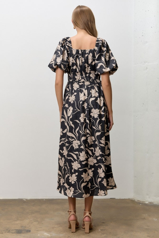 woman wearing a black floral midi dress with puff sleeves and a smocked back view