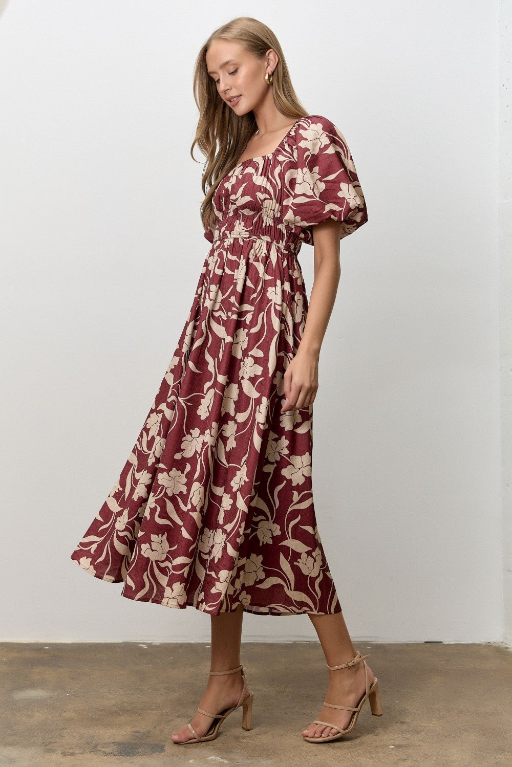 woman wearing a burgundy floral midi dress with puff sleeves and a fitted bodice