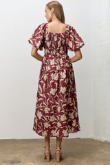 woman wearing a maroon floral midi dress with puff sleeves and a smocked back design