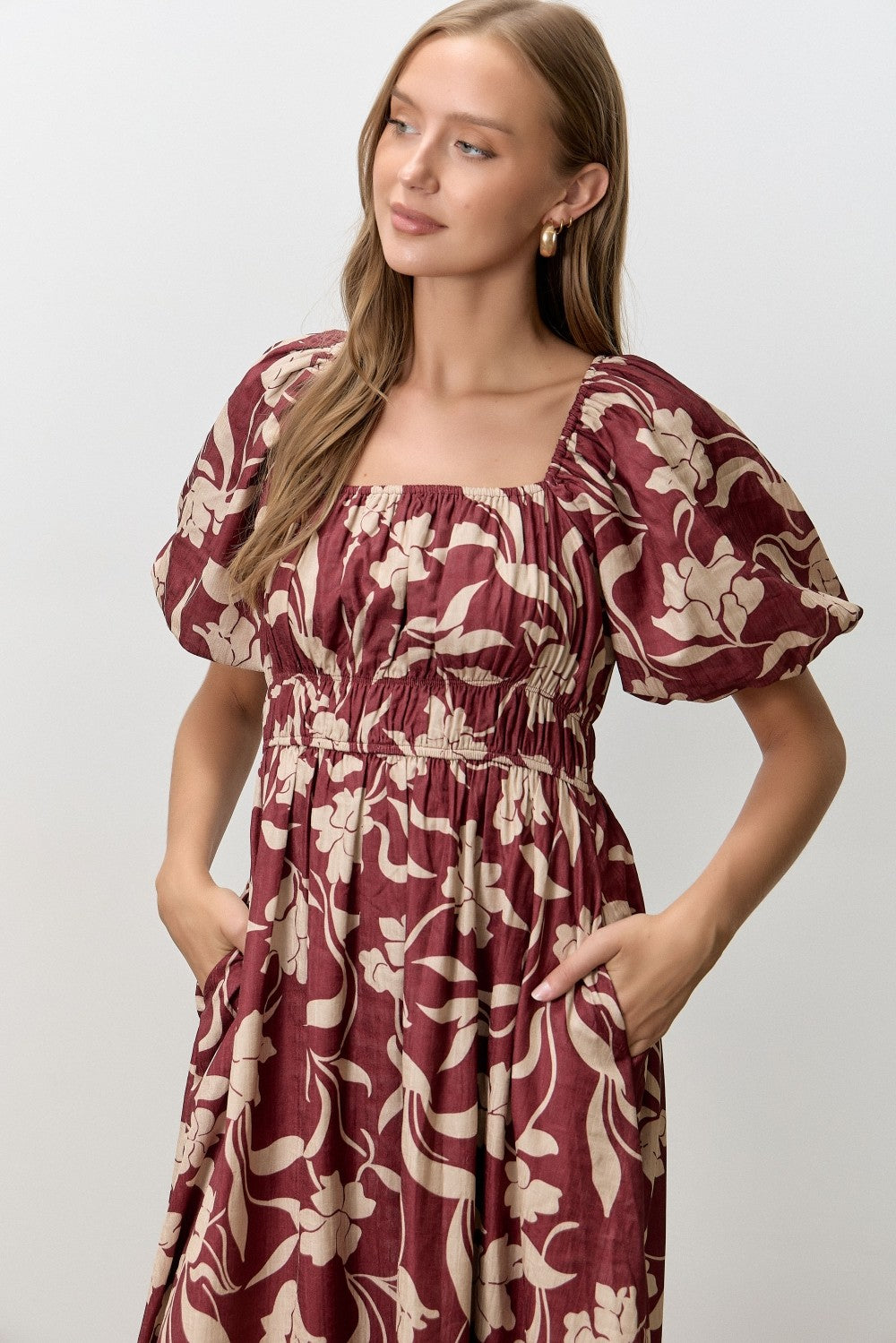 woman wearing a burgundy floral print midi dress with puff sleeves and pockets