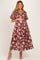 woman wearing a burgundy floral print maternity dress with puff sleeves and holding her baby bump