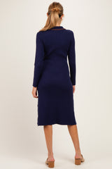 woman wearing a navy blue ribbed long sleeve maternity dress with a mid-calf length and a fitted silhouette