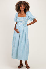 woman wearing a light blue and white striped maternity dress with puff sleeves and a baby bump visible