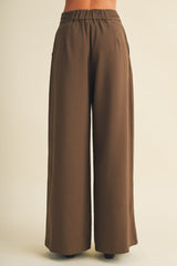 woman wearing brown wide-leg trousers with an elastic waistband and side pockets