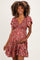 woman wearing a floral maternity dress with short sleeves and a smocked bodice, holding her baby bump