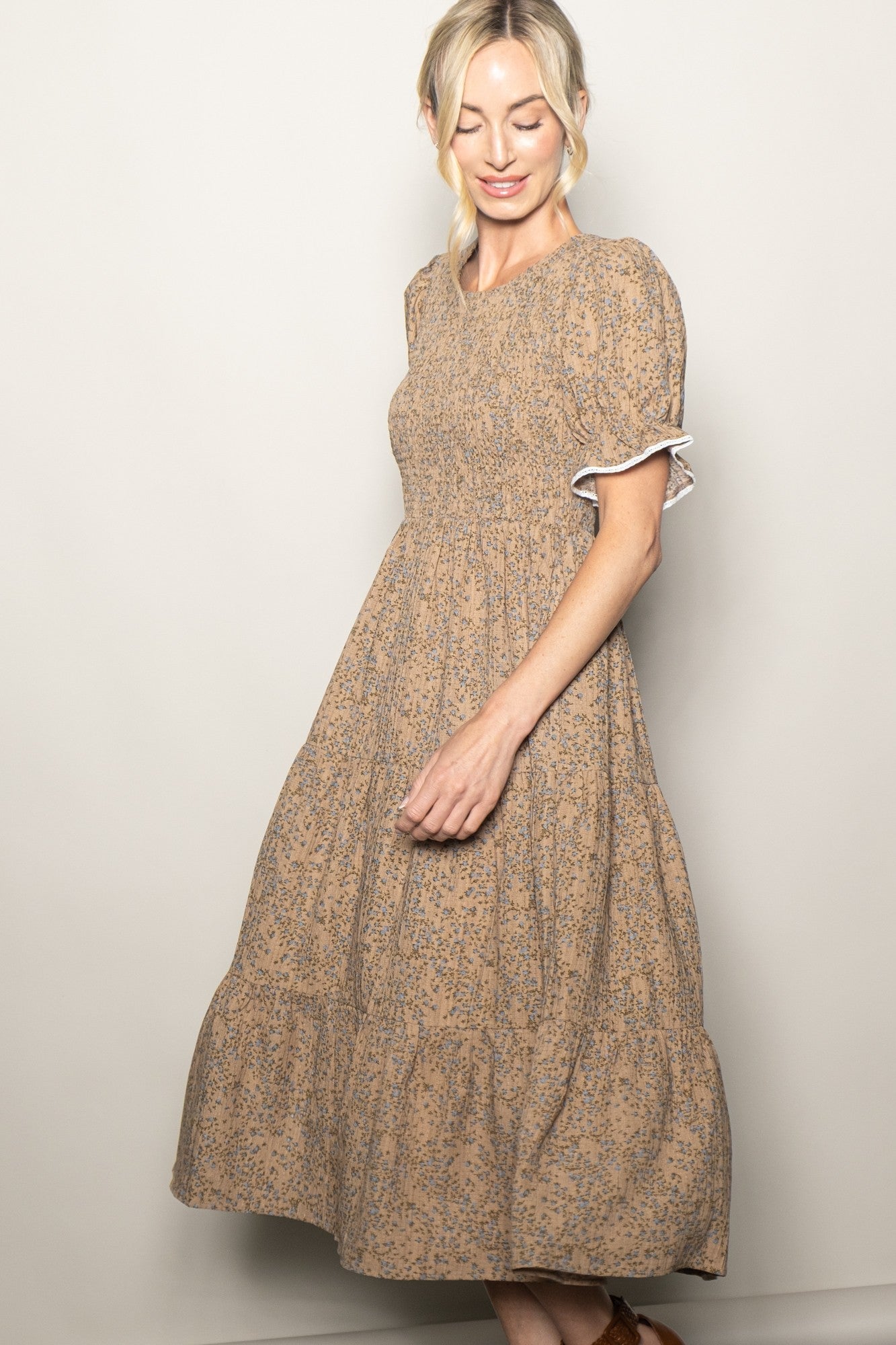 woman wearing a brown floral midi dress with puff sleeves and a tiered skirt