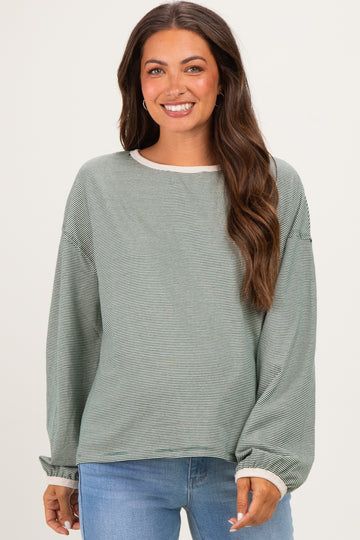 woman wearing a green striped maternity top with long sleeves and a relaxed fit, looking at the camera and smiling