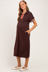 woman wearing a brown maternity dress with a polo collar and striped details, showing her baby bump and pockets