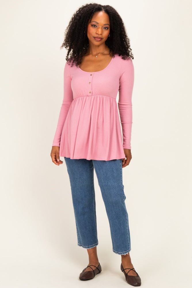 woman wearing a pink long sleeve peplum top with buttons paired with blue jeans