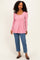 woman wearing a pink long sleeve peplum top with buttons paired with blue jeans
